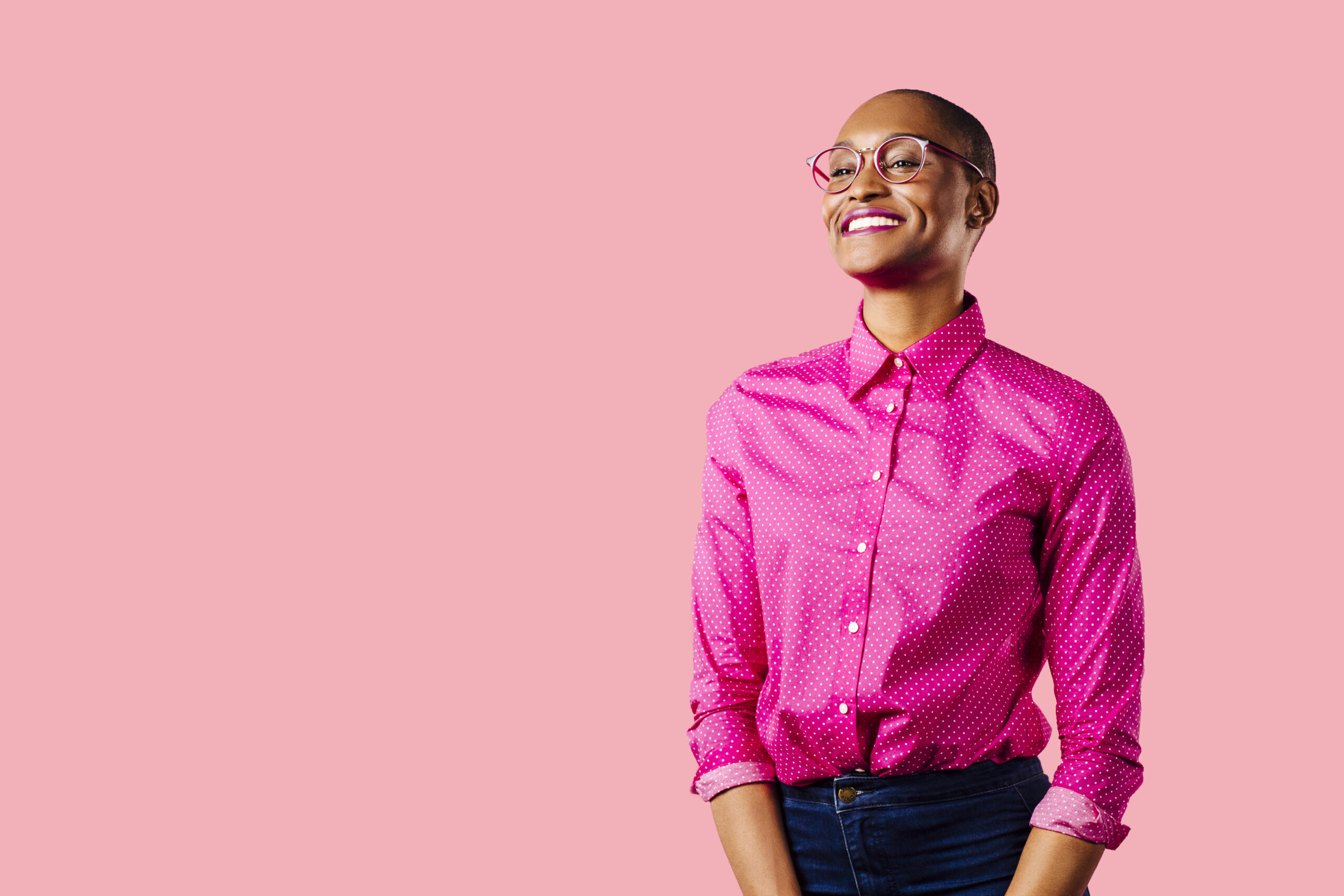 Portrait of a young smiling woman in pink shirt, isolated on pink studio background